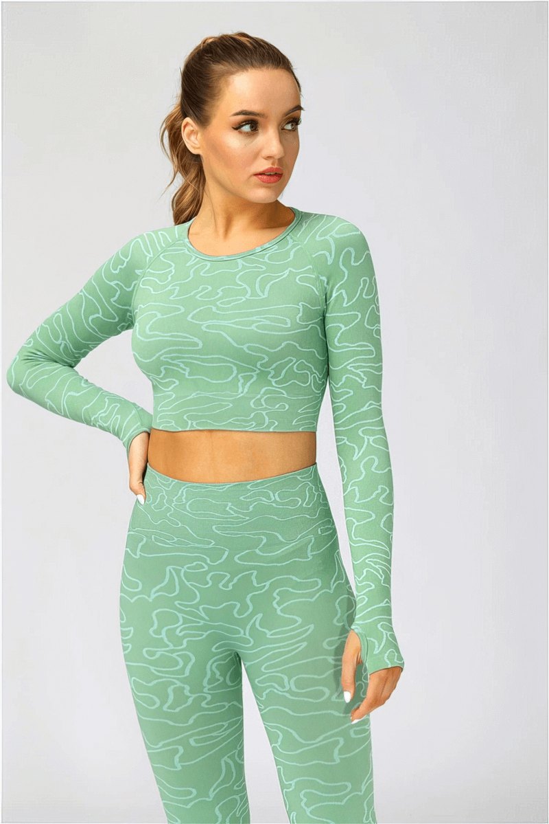 Woman wearing a seamless long sleeve training crop top in green for yoga and running. Comfortable sportswear for female athletes. SF0070